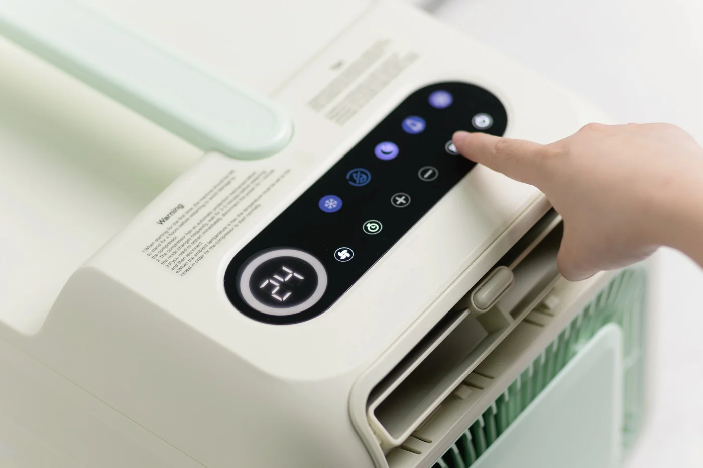A finger pressing the lit control panel, temperature reading 24